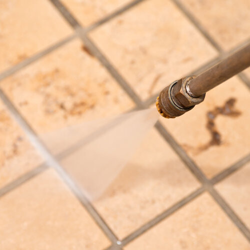 close-up of dirty commercial tile floor being pressure washed