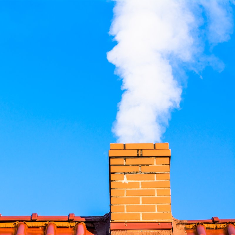 smoking brick chimney on top of a roof