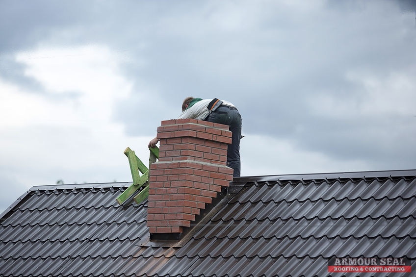 Worker on Roof Behind a Chimney Making Repairs